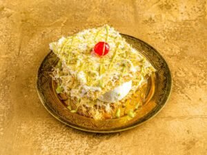 Grande kunafa topped with ice cream, pistachios, cream and cherry